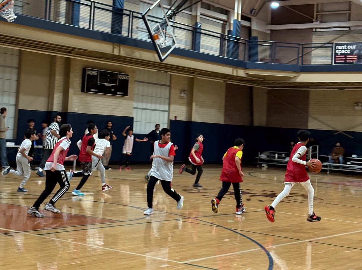 A boys basketball game with a referee and families watching.
